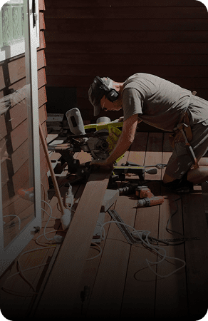 Person cutting wood with a miter saw in a workshop.