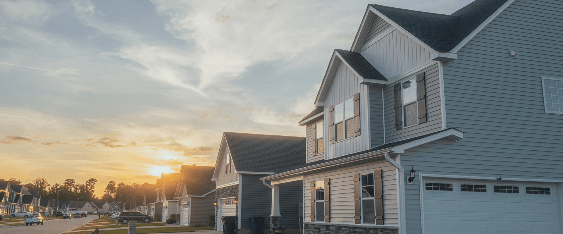 Suburban houses at sunset with cloudy sky.